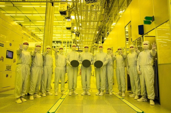 A team at a Samsung Electronics’ semiconductor foundry poses with circular disks of polished silicon, also called wafers, which are the standard products of a chip foundry.